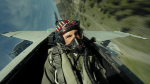 Maverick in Top Gun Maverick sitting in the cockpit of his plane wearing a helmet and mask