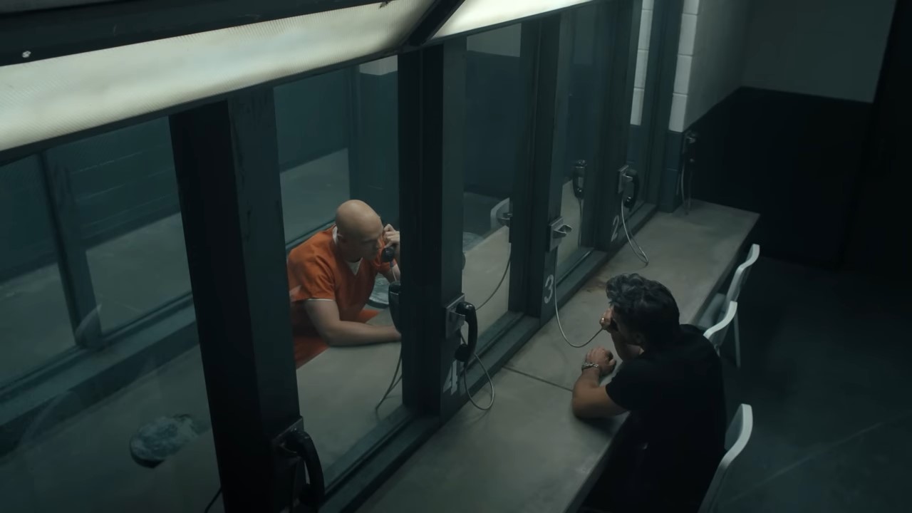 Looking down on two men talking on prison phones