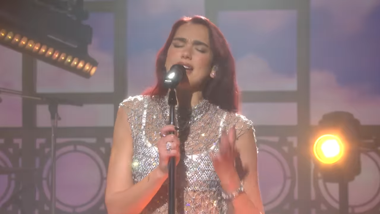 A young woman, eyes closed, sings passionately into a microphone