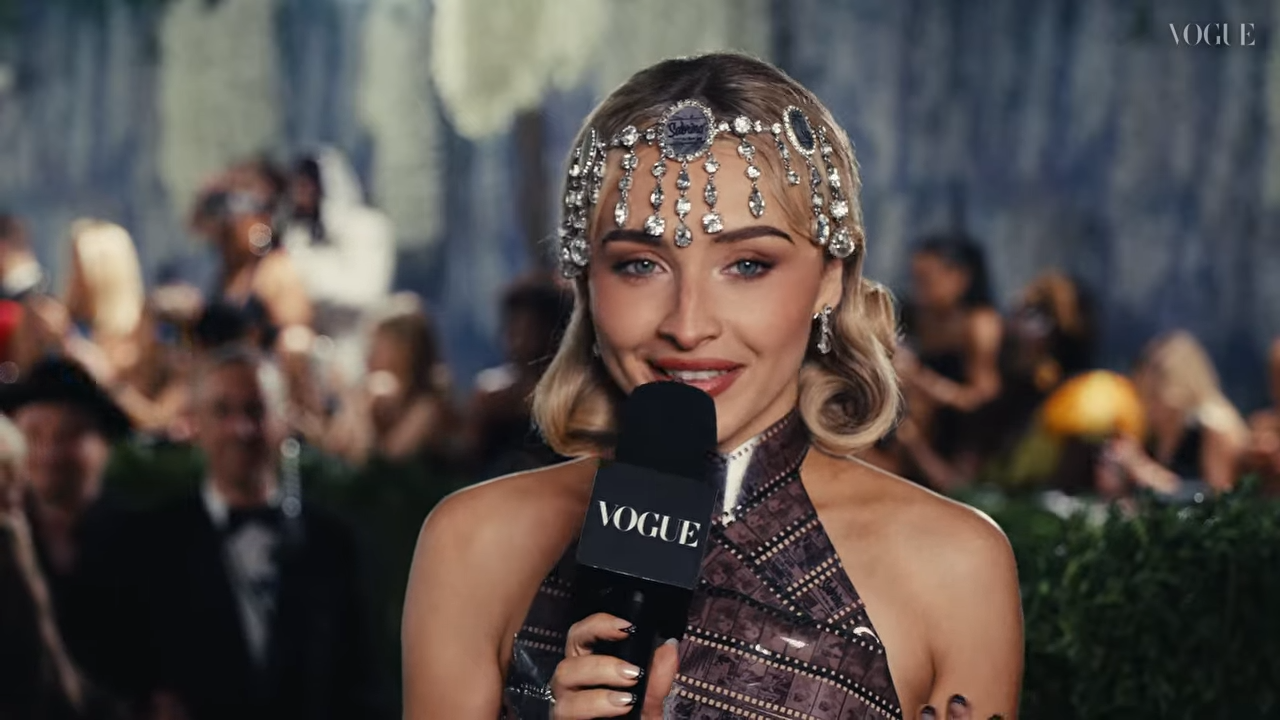 A young woman in 1920's fashion is interviewed at a formal event