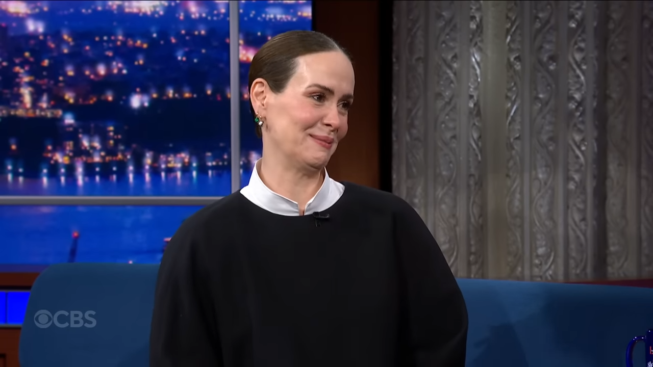 A woman seated on a late show stage