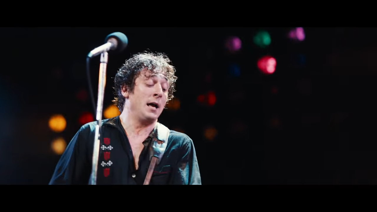 A sweaty man performs on stage at a rock concert