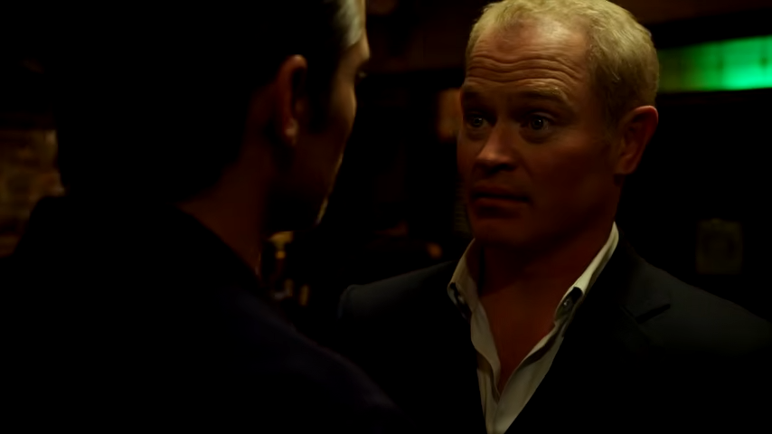 Two men facing off in a dark bar