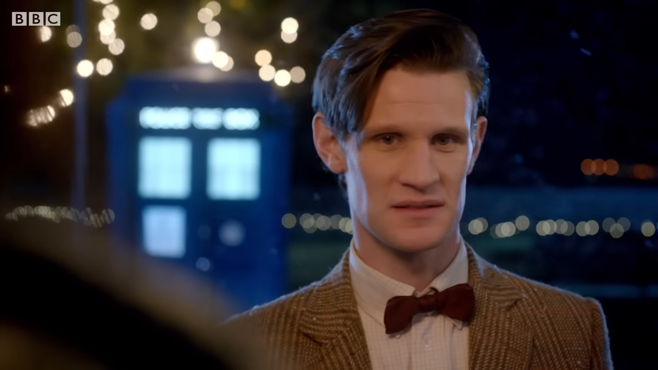(6) The Doctor Visits Amy & Rory For Christmas The Doctor, the Widow and the Wardrobe Doctor Who 00-00-37 Doctor Who in a bow tie stands outside with the TARDIS behind him framed in Christmas lights. He seems uncertain.