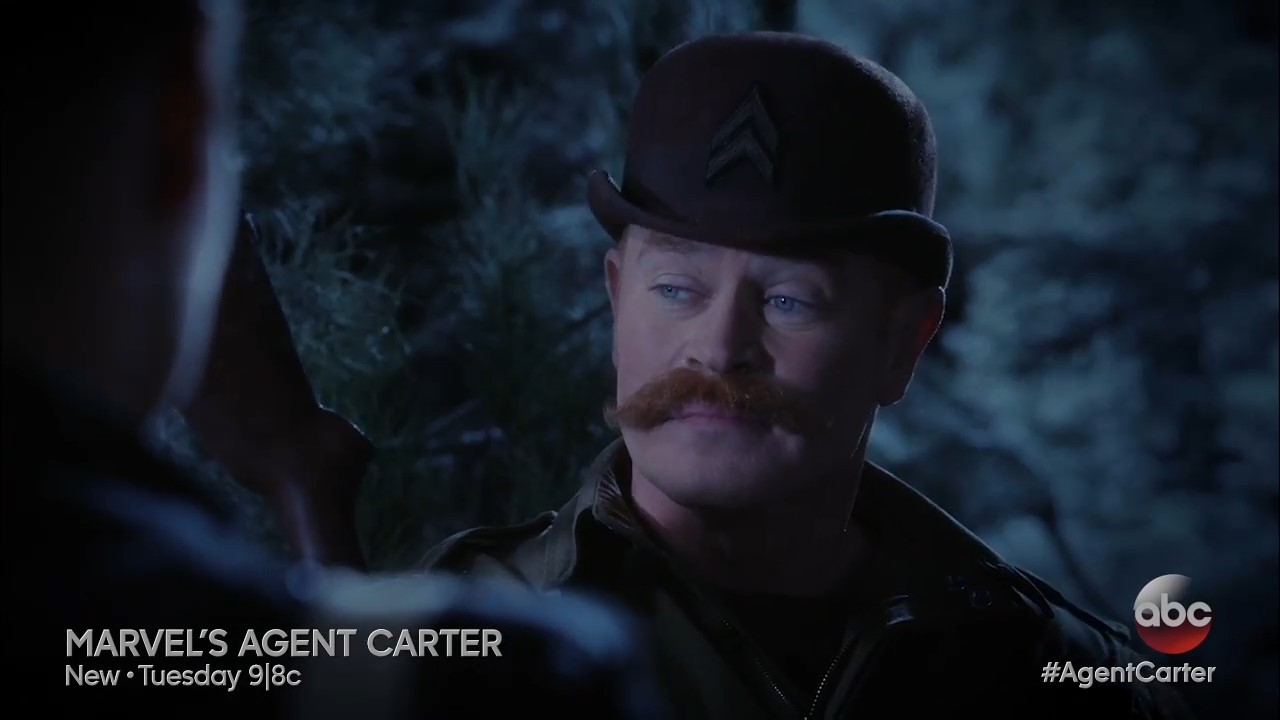 A man in a bowler hat and large mustache looking confident in a dark forest