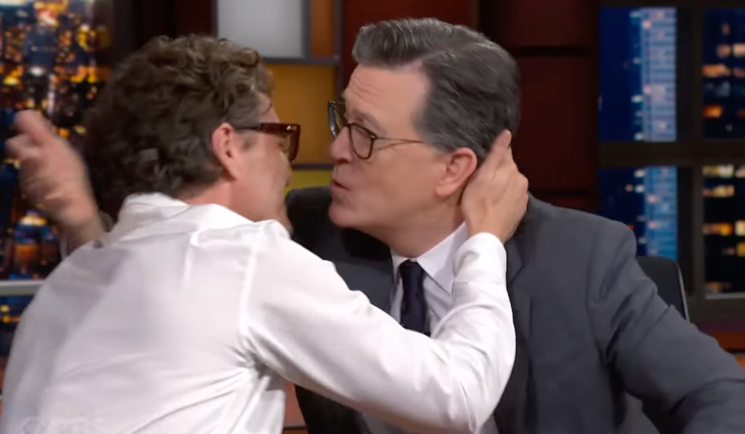 Pedro Pascal and Stephen Colbert lean toward each other to kiss