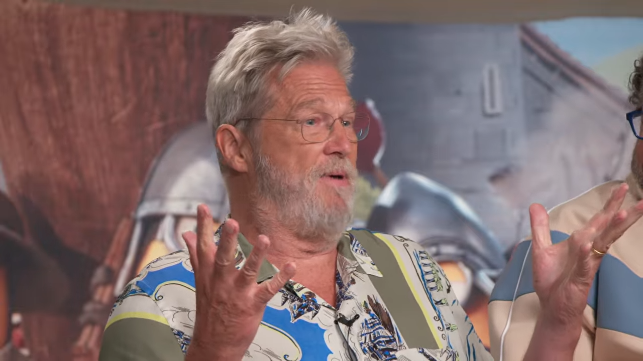 Jeff Bridges lifts both hands, palms up