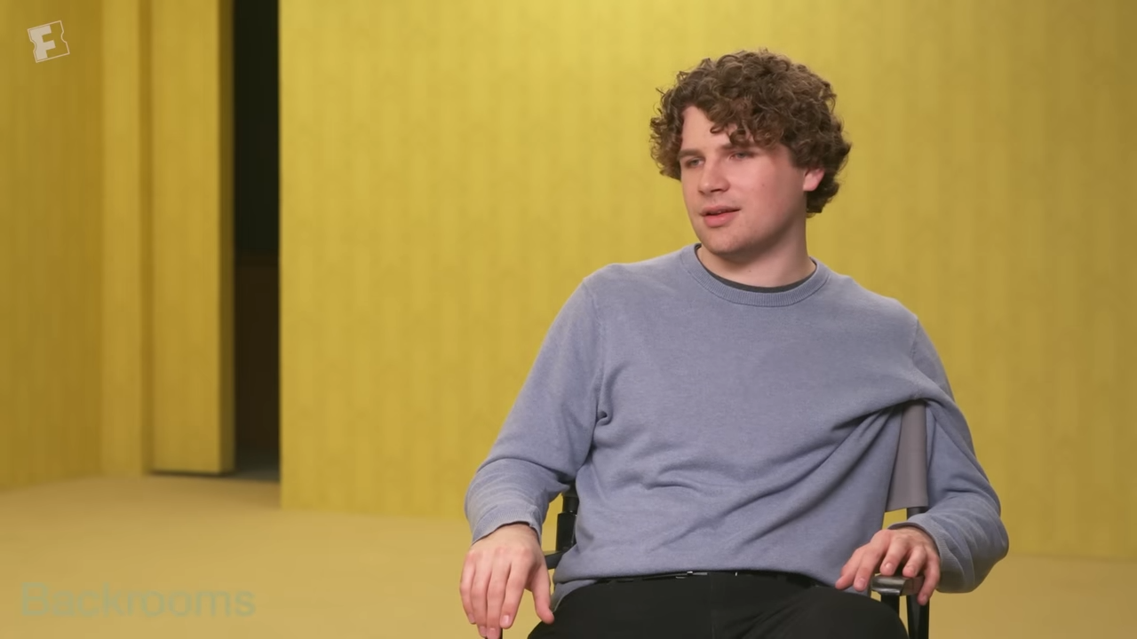 Kane Parsons sits in an empty office space with sickly light for an interview
