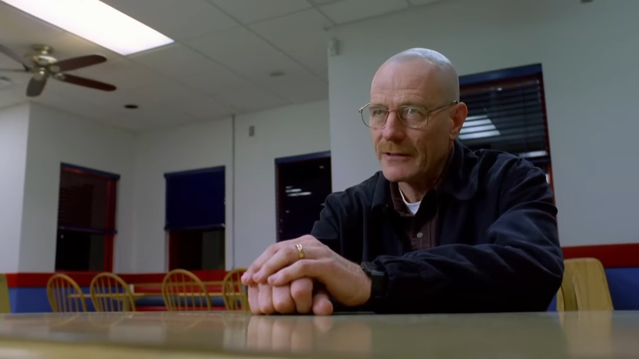 A man sits at a table, hands folded