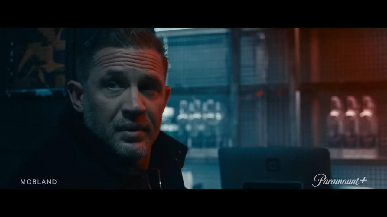 A man with a wry look in a dark room
