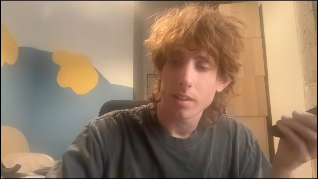 A young man sits inside, holding his phone.