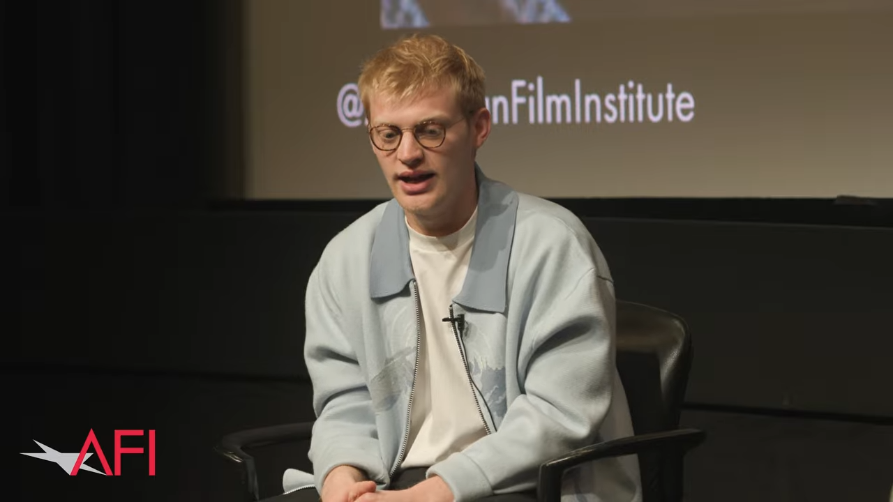 A young man sits on stage for an interview