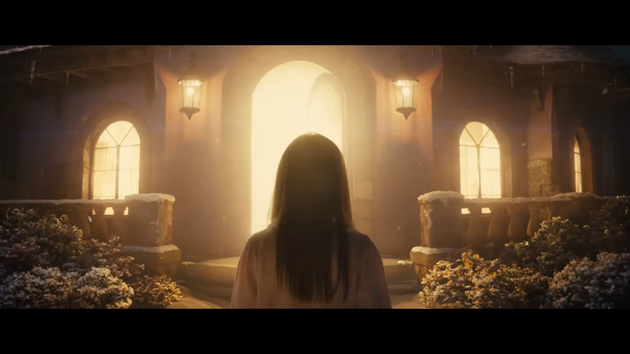 A girl stands facing a house that is filled with light