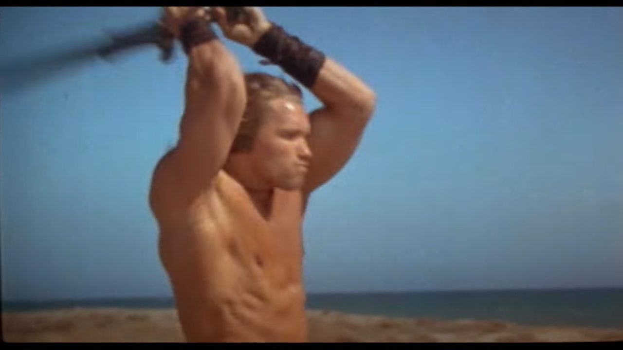 A huge, muscular man lifts a sword over his head