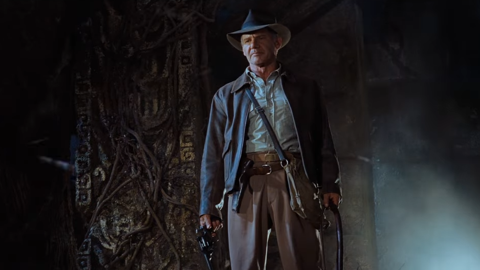 Indiana Jones stands in a cave, looking confident