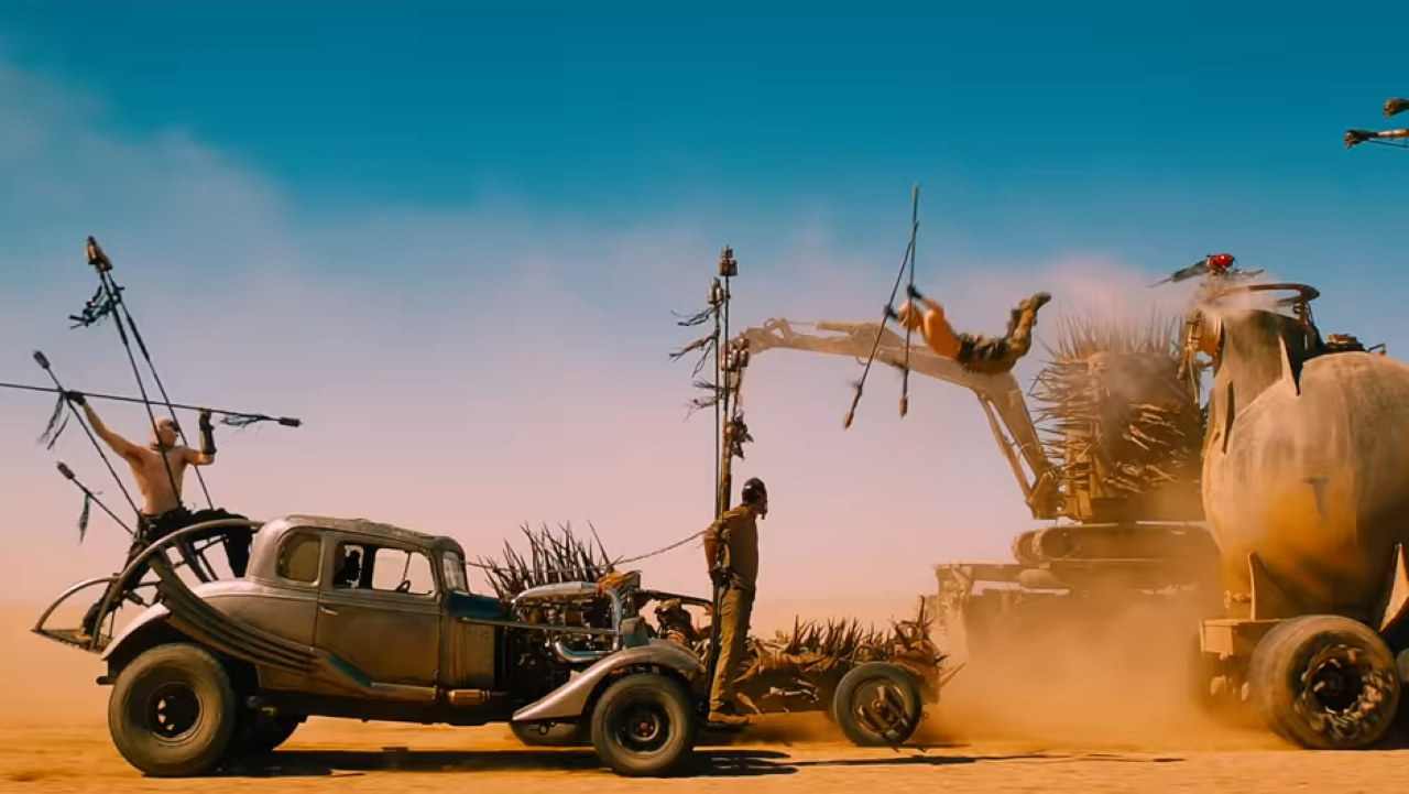 A post-apocalyptic car chase with a warrior leaping onto the hood of a car