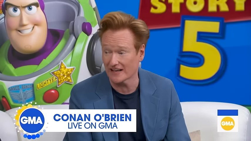 Conan O'Brien sits in front of Toy Story 5 artwork