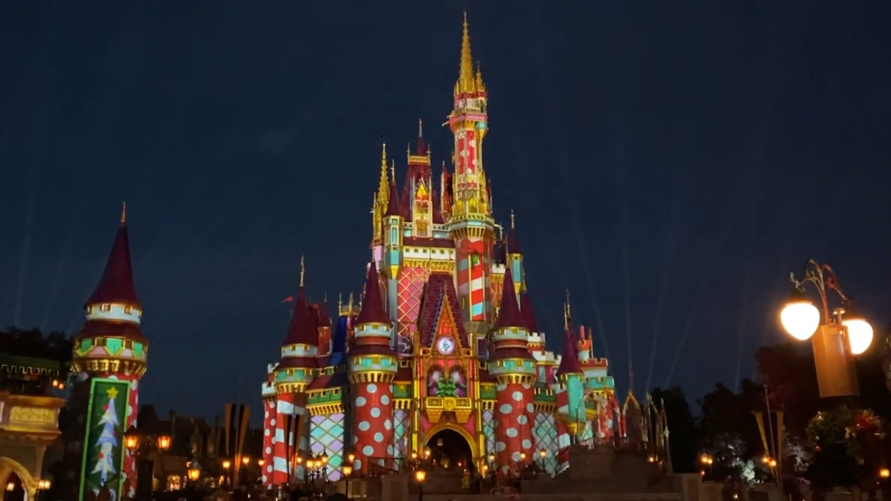Cinderella Castle at night lit with red, green, and gold projected colors