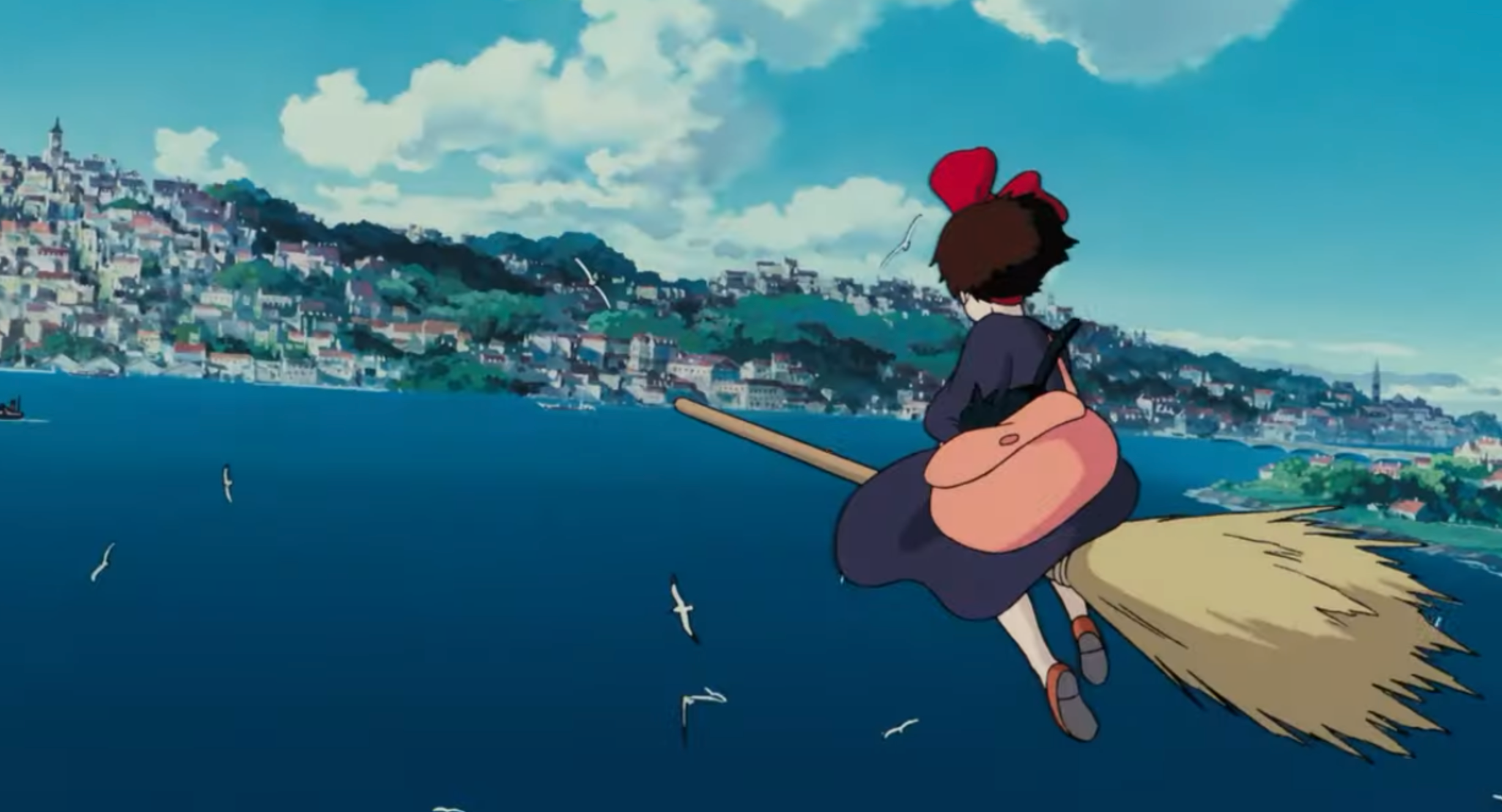 Kiki flying on her broom toward a town