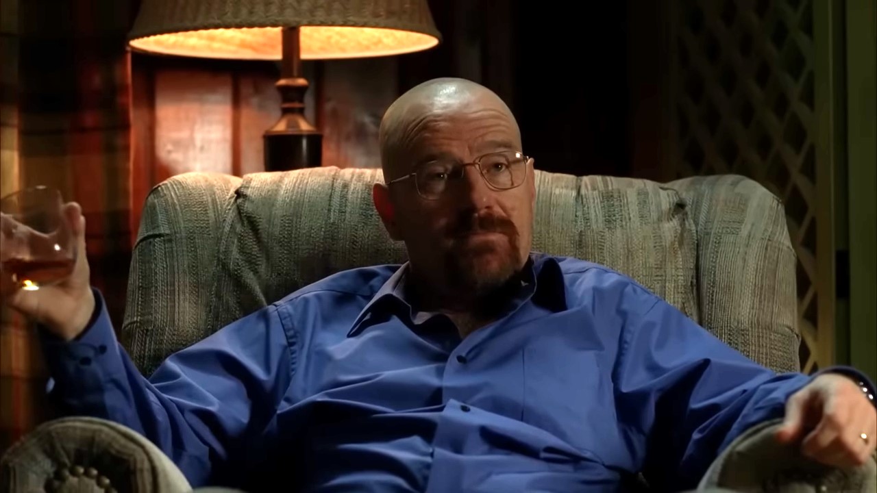 A man reclines in a chair, lifting his drink
