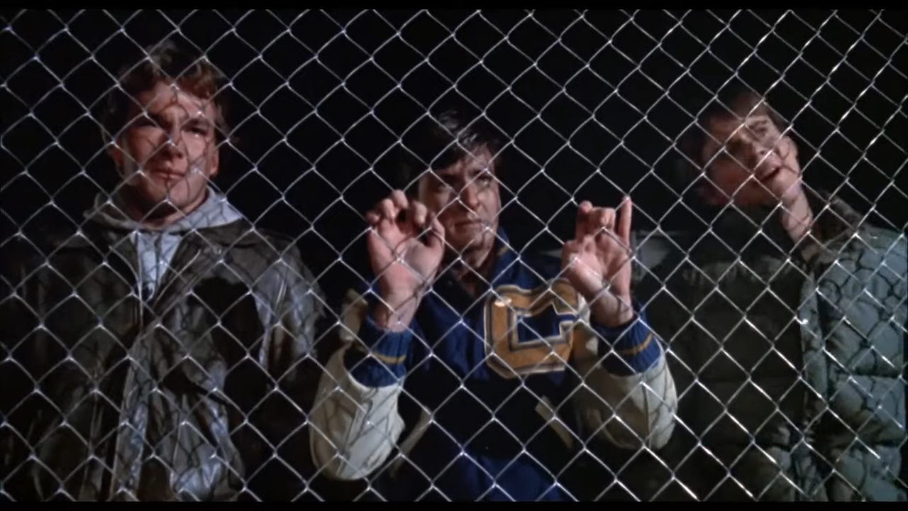 Three men are imprisoned behind a fence