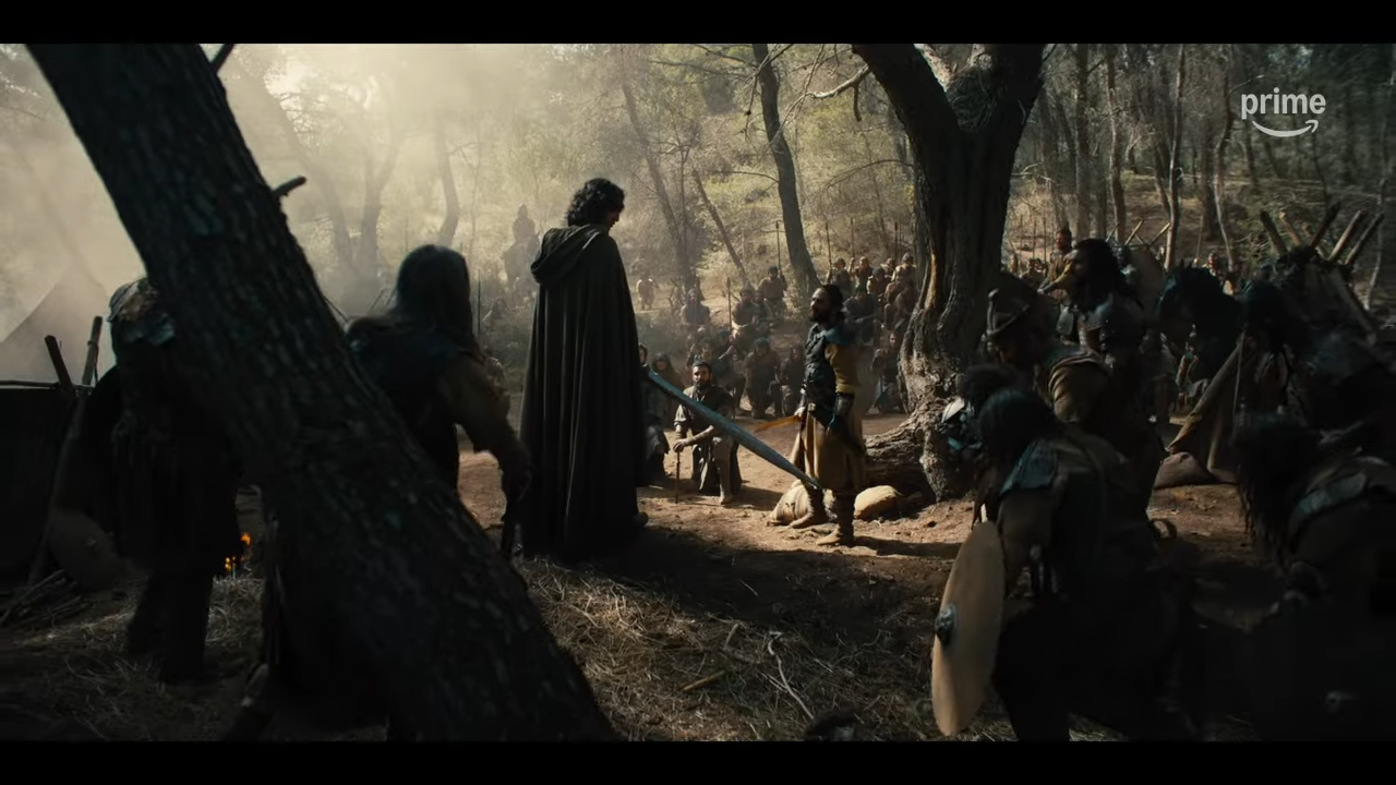 Soldiers in a forest kneel before a man