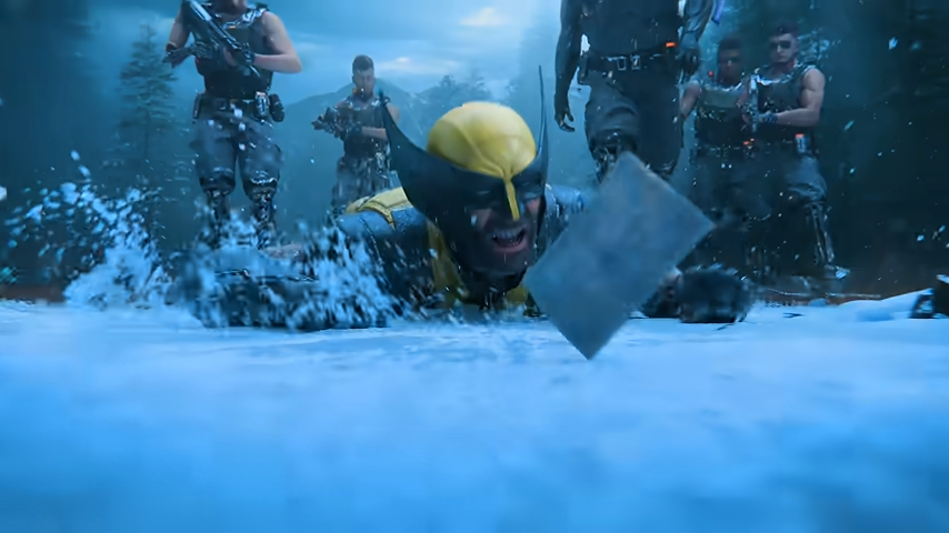 Video game image of Wolverine, having fallen in the snow and surrounded by attackers, reaching for a photograph