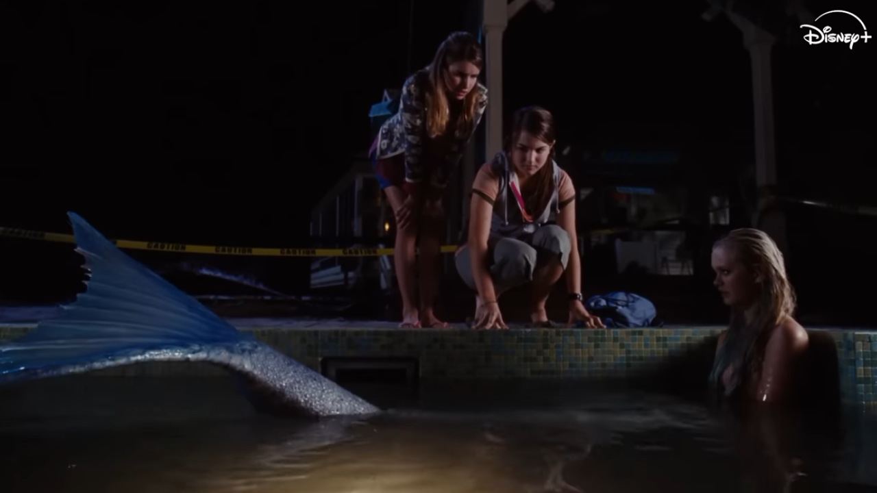 Two girls in the dark watching a mermaid