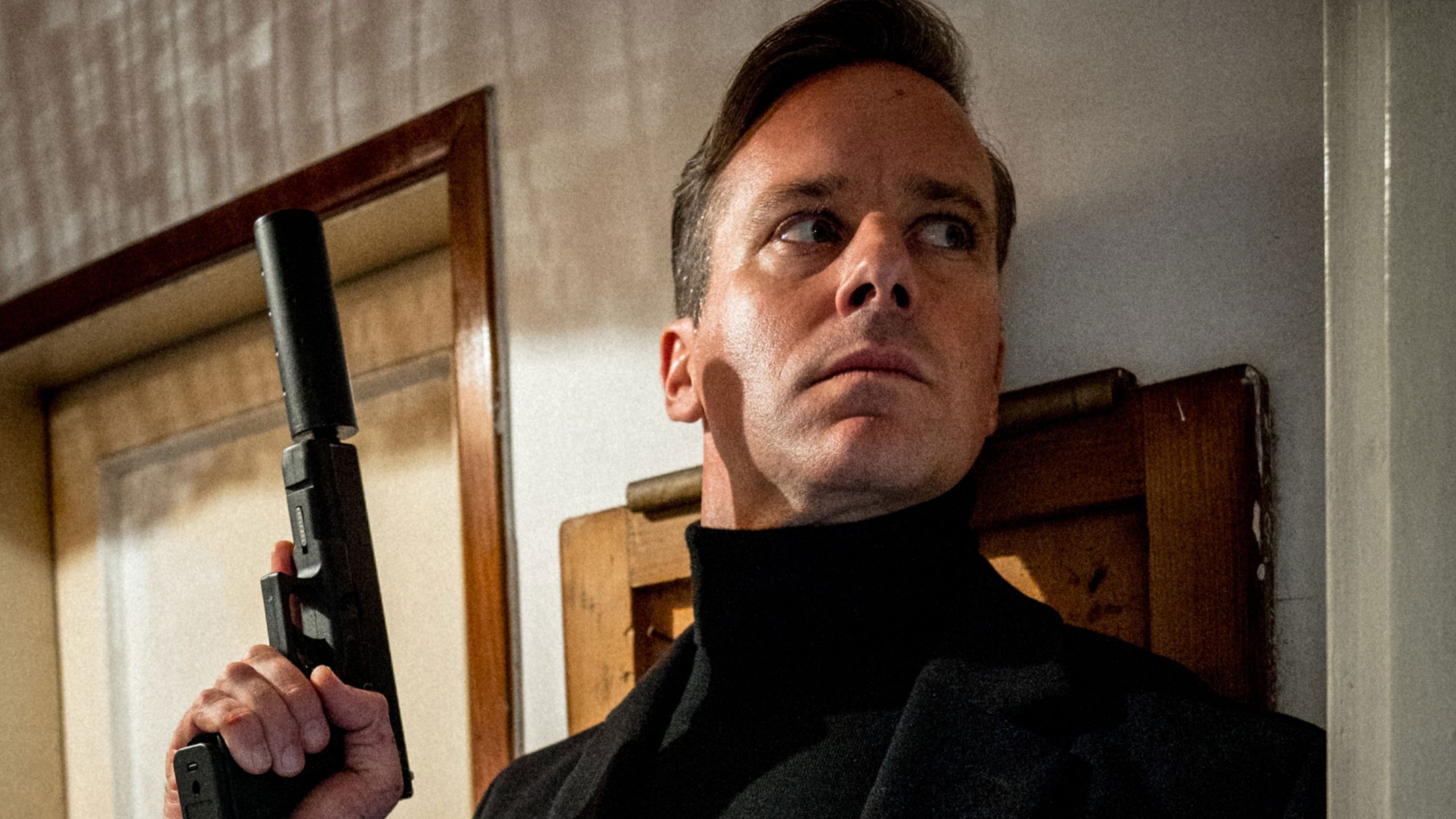 Armie-Hammer-Citizen-V-scaled A man in profile holds a gun