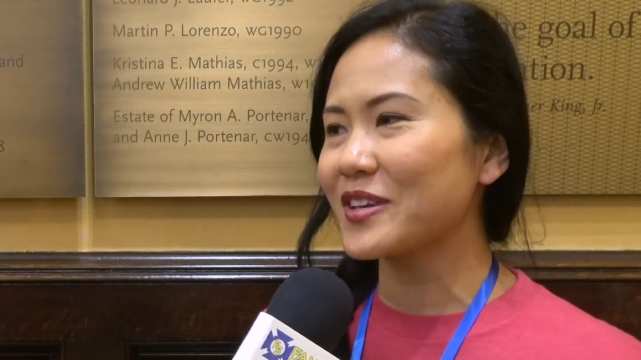 A woman speaking into a microphone for a fan interview