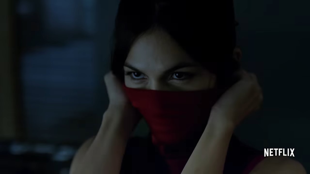 A woman playfully holding a cloth up to her face so that only her eyes show.