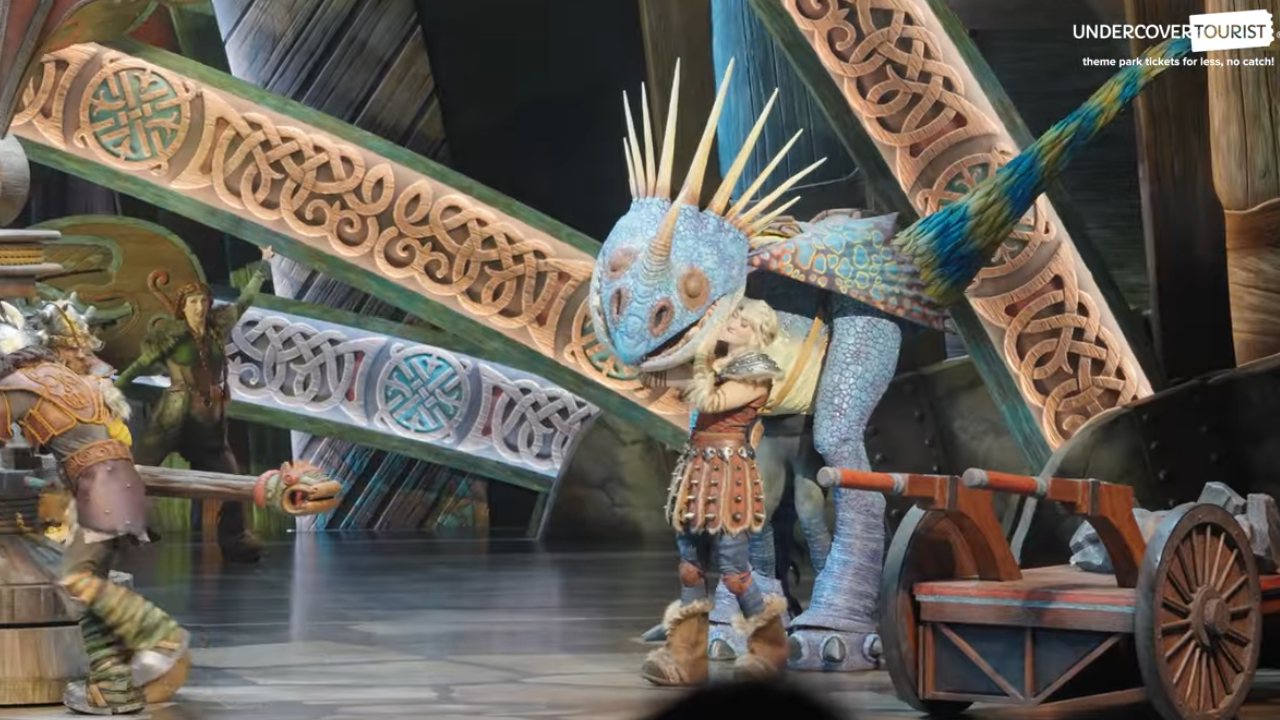Viking woman giving a hug to a large blue dragon onstage