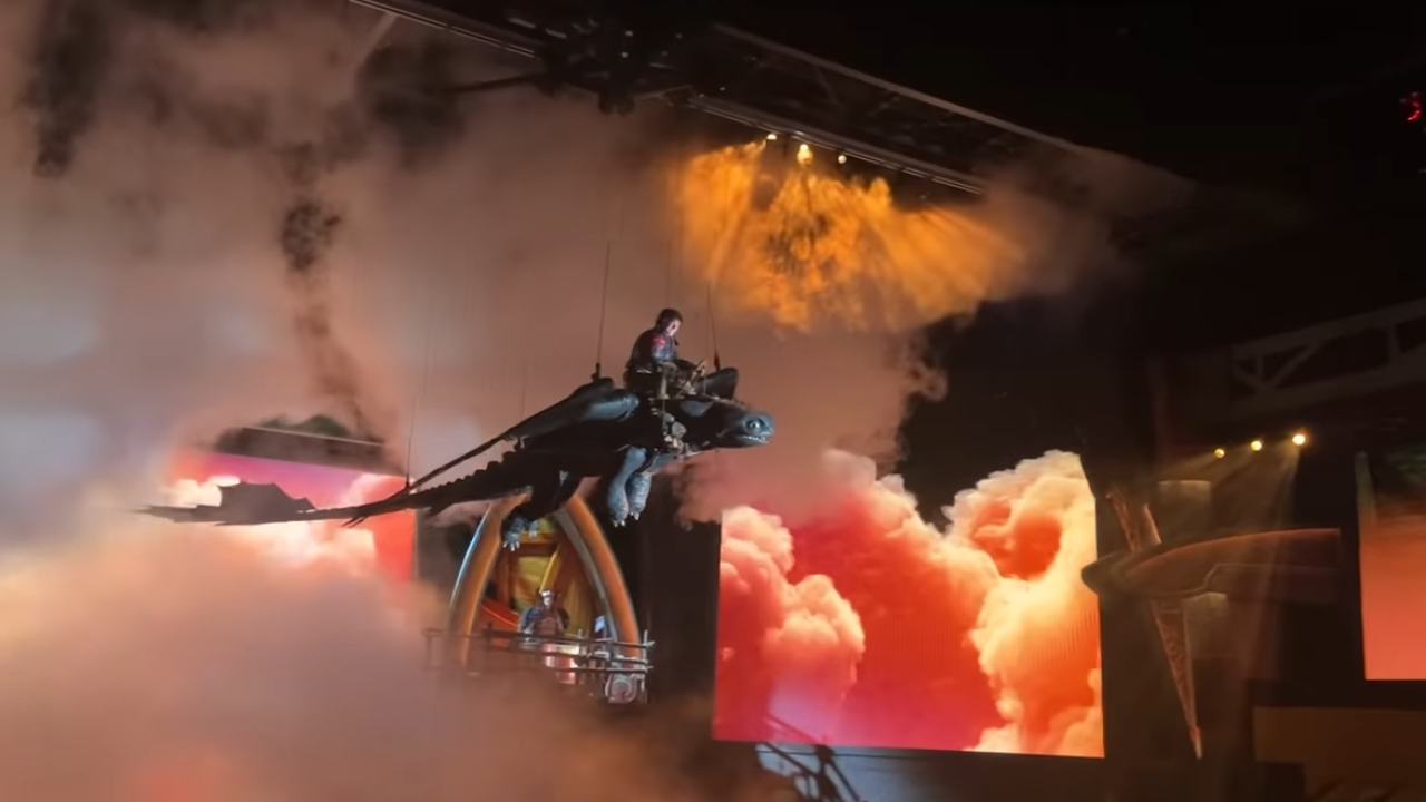 Puppet dragon with actor suspended above the stage as smoke billows behind them