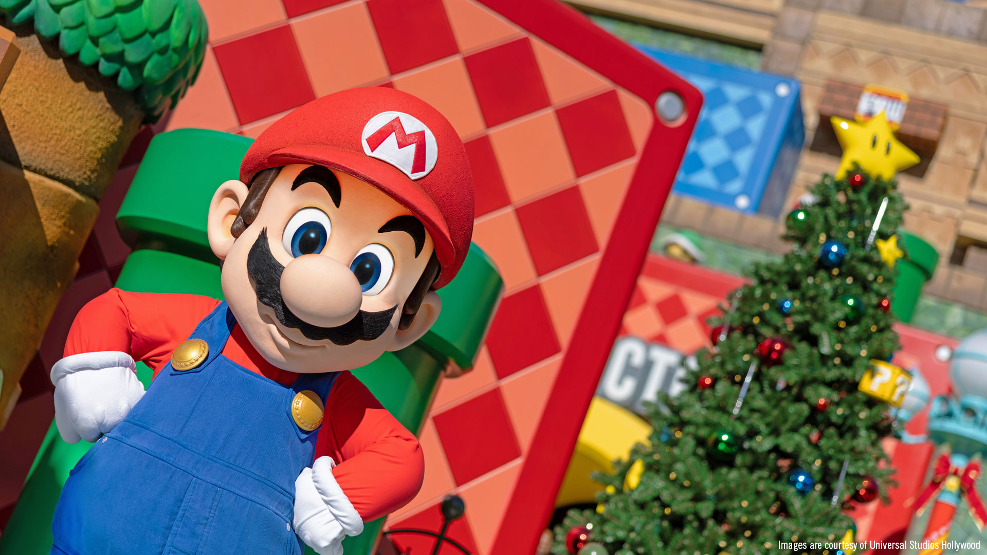01_SUPER NINTENDO WORLD Mario standing in front of textured scenery with a Christmas tree in the background