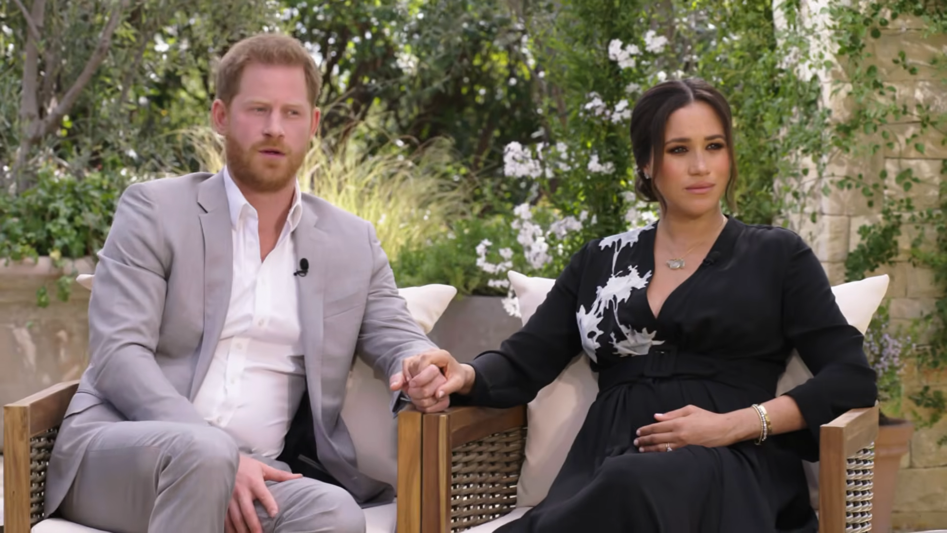 Prince Harry and Meghan Markle seated and holding hands
