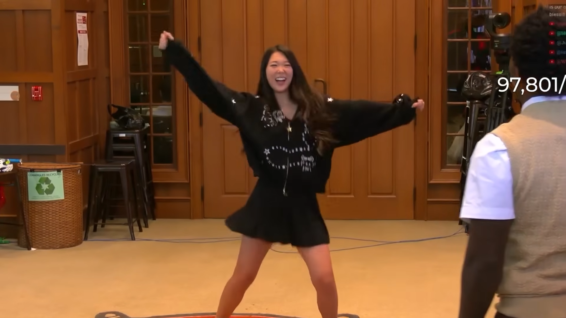 A young woman in a shirt skirt and a jacket with long sleeves dances energetically