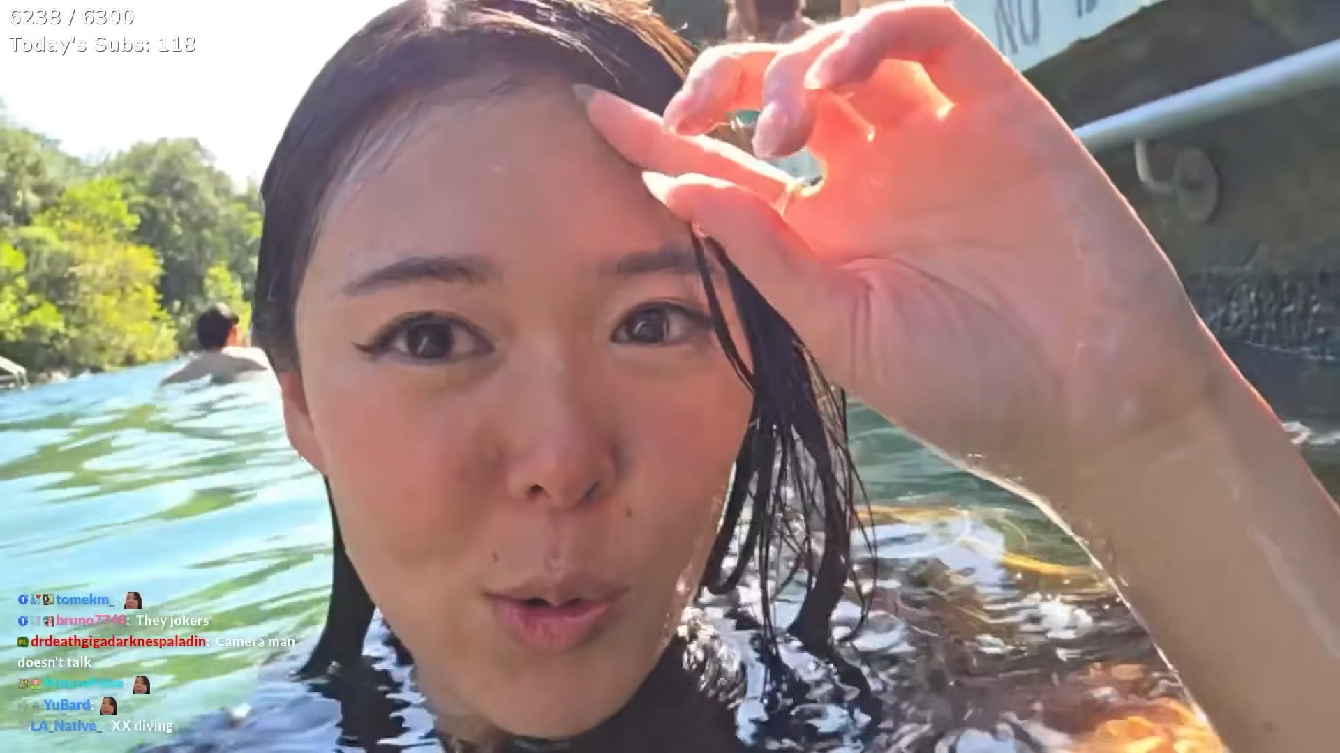 (131) Extra Emily Goes To Barton Springs! 00-12-42 A girl up to her neck in the water fixes her hair while live-streaming into her phone