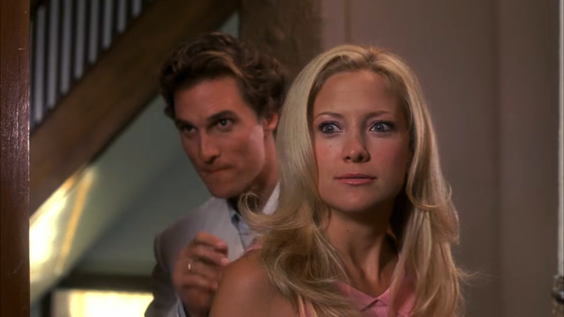 A man stands behind a woman. They both appear to be scheming.