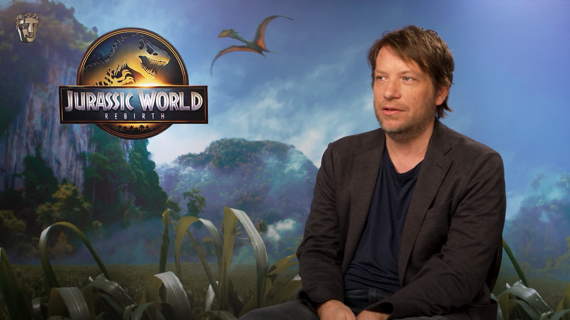 (219) How Jurassic Park Rebirth was made to feel like a lost 90s film, recapture Spielberg feeling BAFTA 00-00-30 Gareth Edwards sitting in front of a Jurassic World backdrop