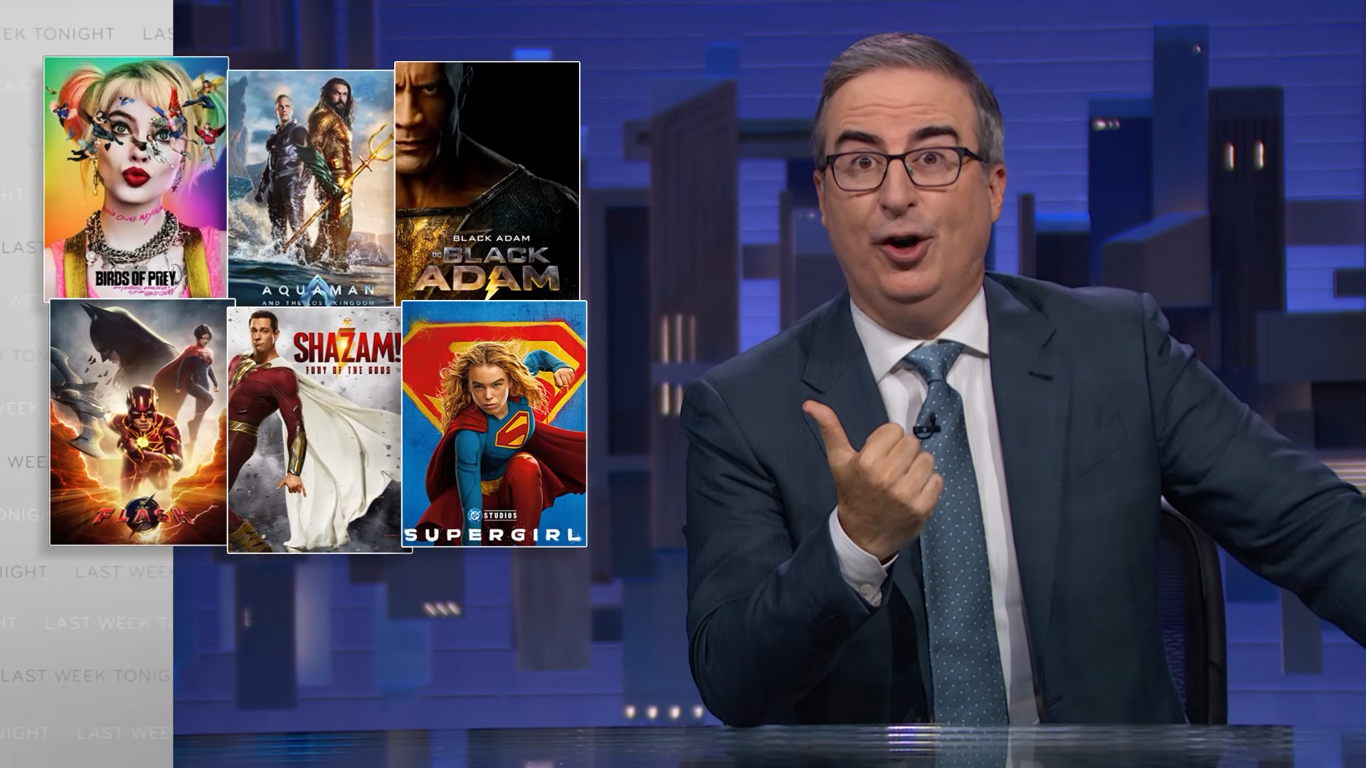 (271) Trump & the DOJ Last Week Tonight with John Oliver (HBO) 00-12-09 John Oliver next to a graphic with DC Studios movie posters