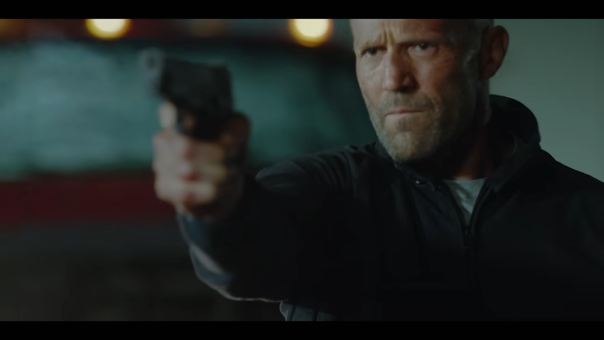 A stern-faced man firing a handgun