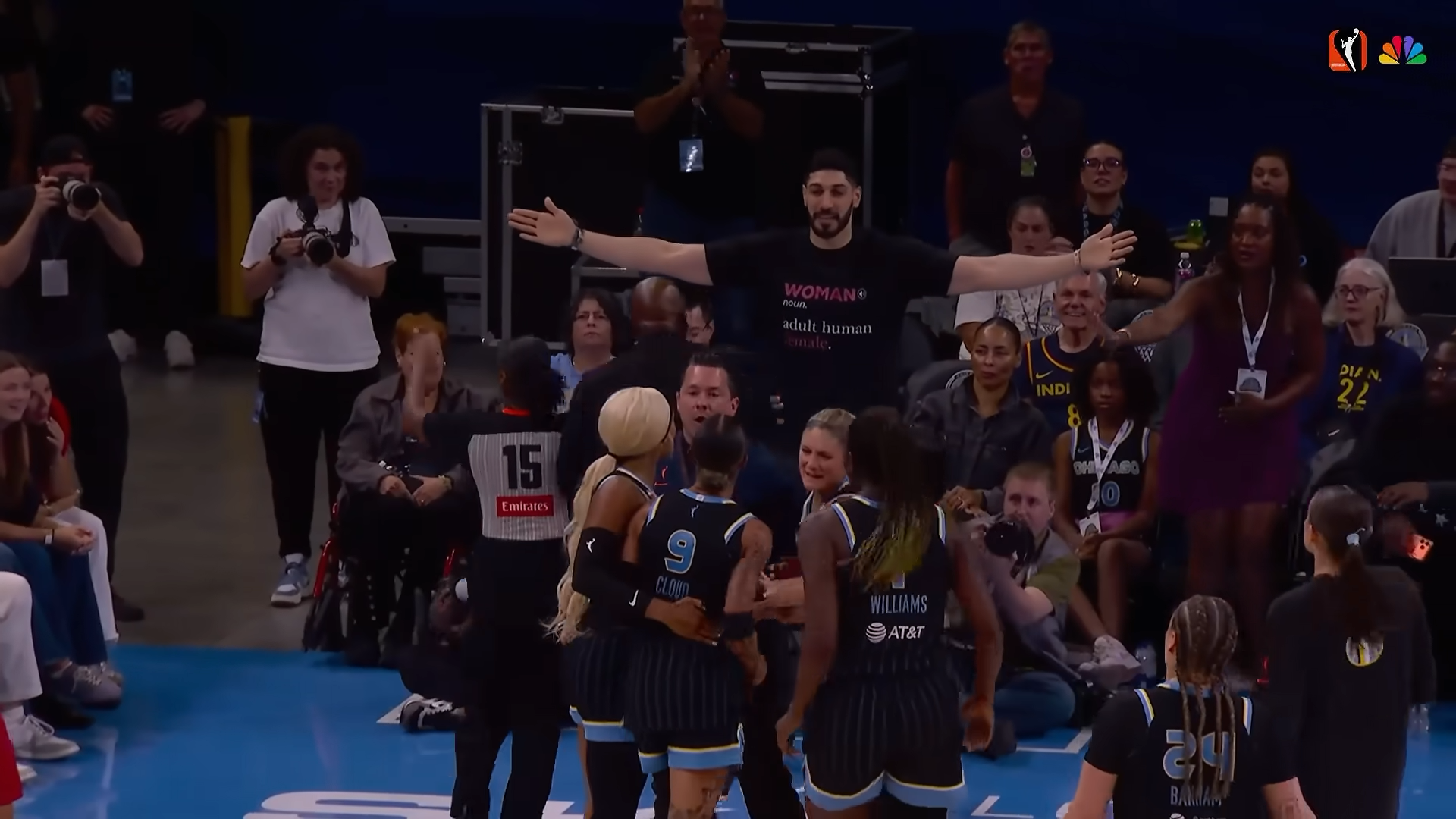 Enes Kanter Freedom stands with his arms outstretched as WNBA players aggressively approach him