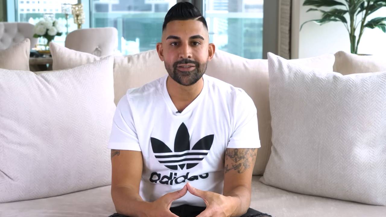 A man speaks directly into the camera from his bright living room