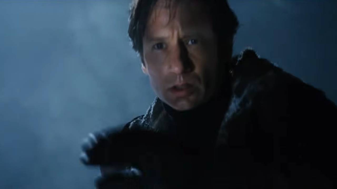 Fox Mulder with snow falling behind him, looking at something frightening