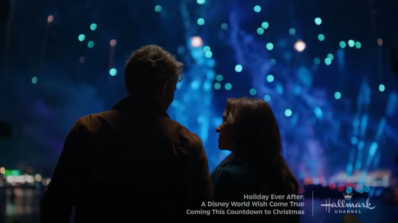 Image of couple' silhouette against blue fireworks lighting up the night sky