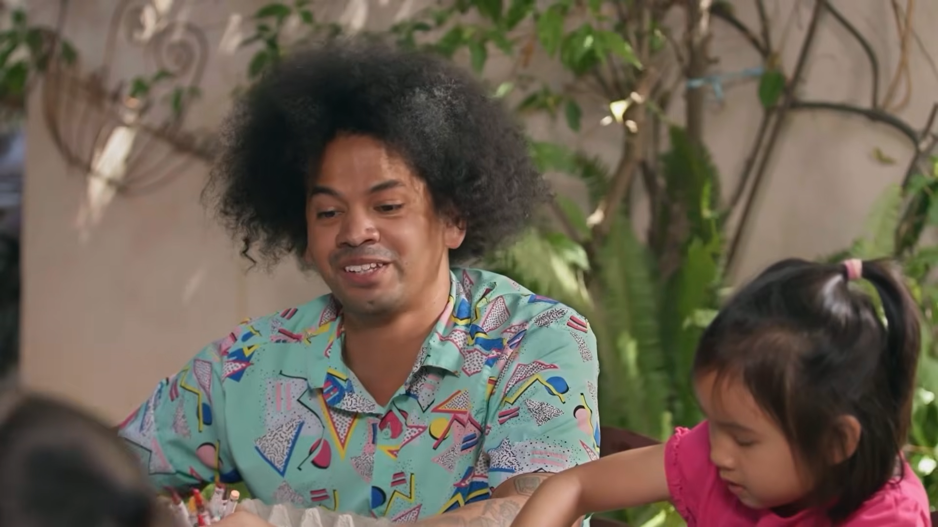 Mychal Threets sits at a table with children
