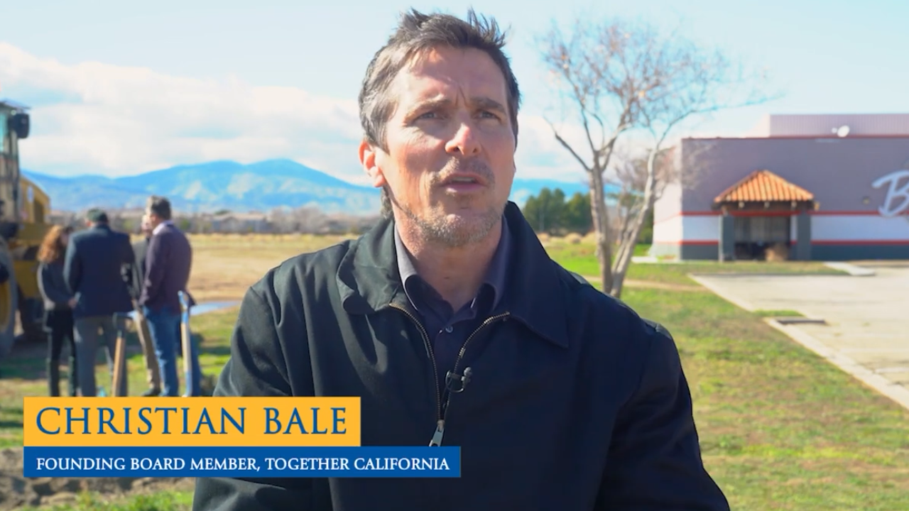 Christian Bale standing outside near construction vehicle