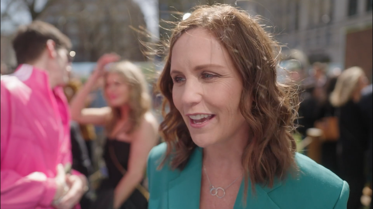 Kayleen Walters speaking to a reporter at an outdoor event, smiling