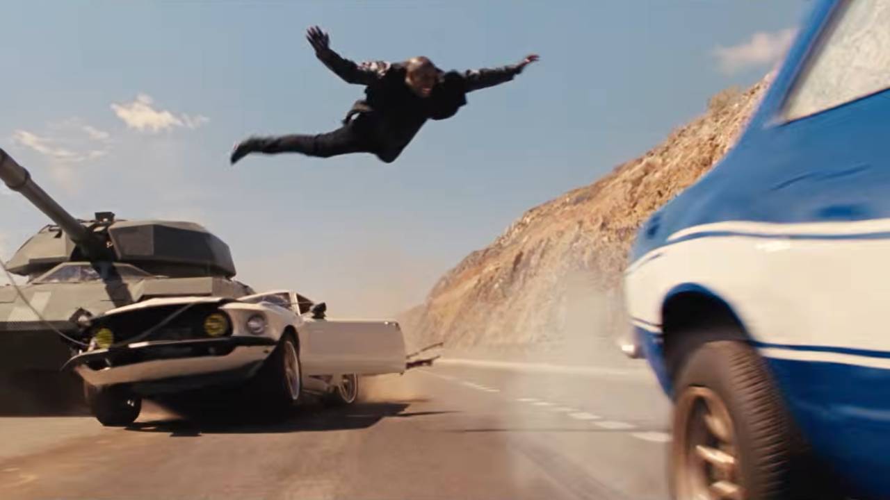 Fast 6 Roman leap A man flies through the air between a car being crushed by a tank and another speeding car