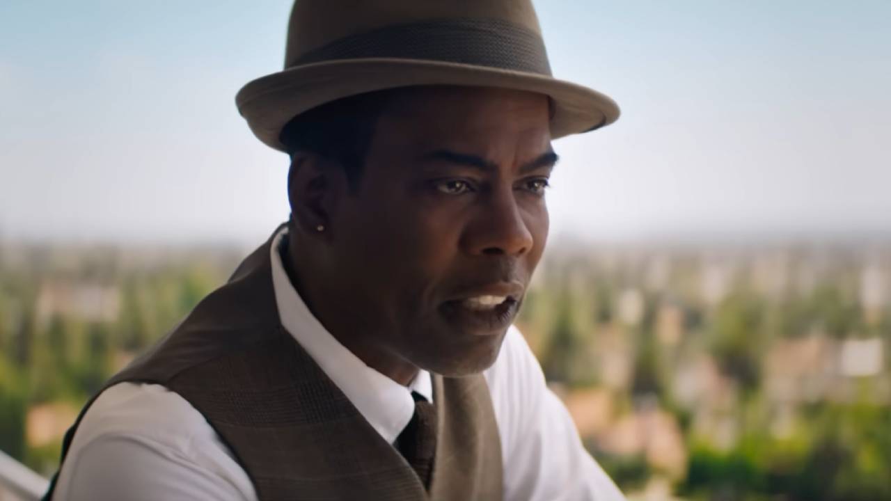 Chris Rock in a hat and vest making a serious point